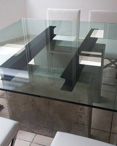 bases de cemento, bigas de acero y tope de cristal para crear una mesa moderna